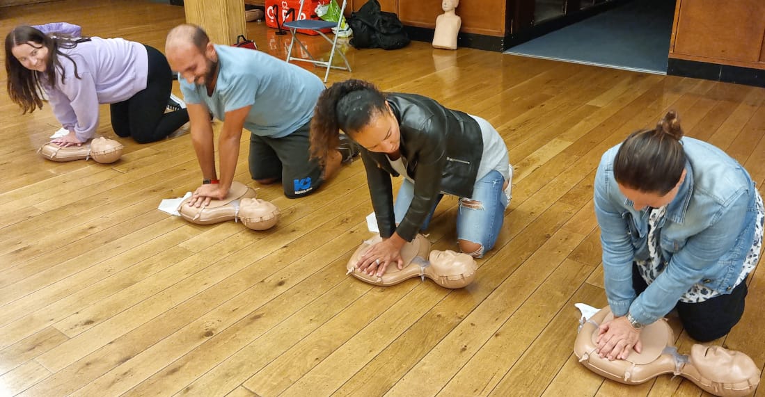 Group of adults practising CPR chest compressions on training manikins during a community first aid session
