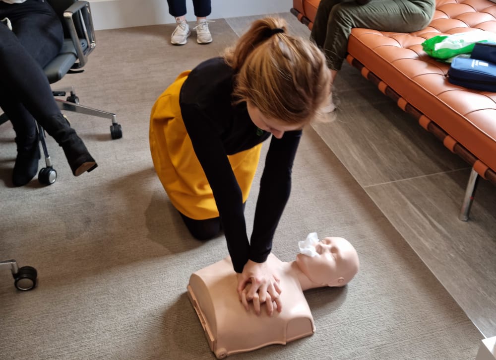 Workplace first aid training session practising CPR on a manikin