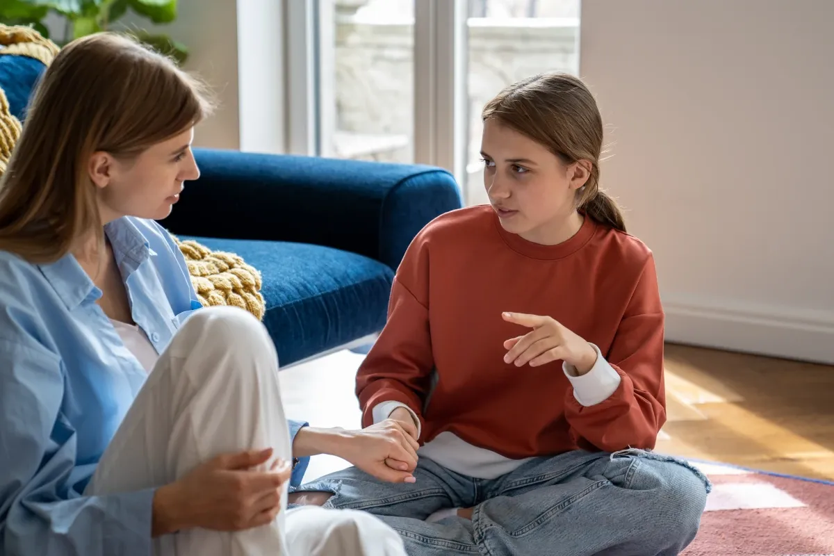 Mother and teenage daughter sitting on the floor having a calm conversation