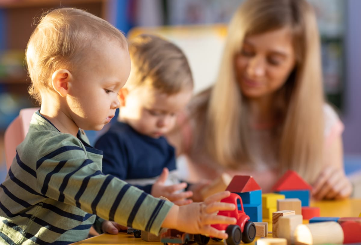 Nursery practitioner supervising young children during play session