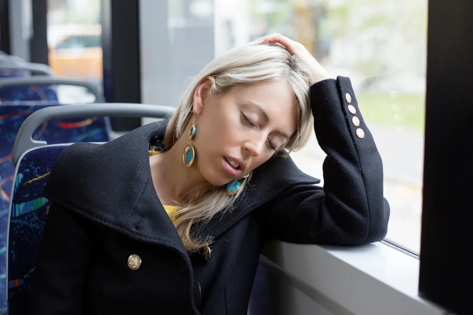 Tired woman resting with her eyes closed on a bus during a morning commute