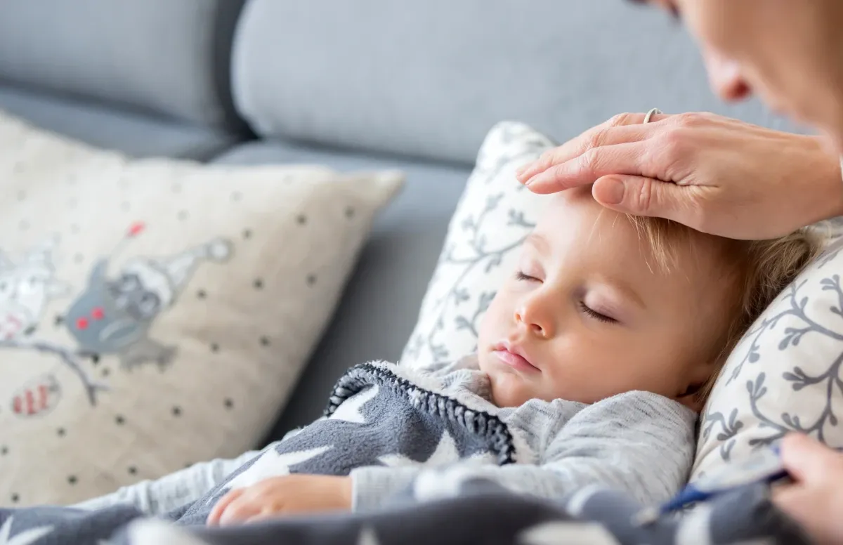 Parent checking temperature of unwell toddler at home