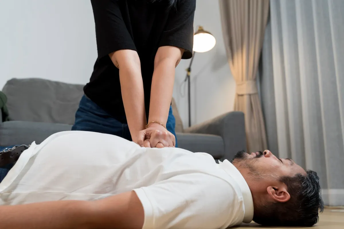 Woman performing chest compressions on an unresponsive man at home