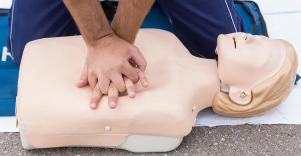 Hands performing chest compressions on a CPR training manikin.